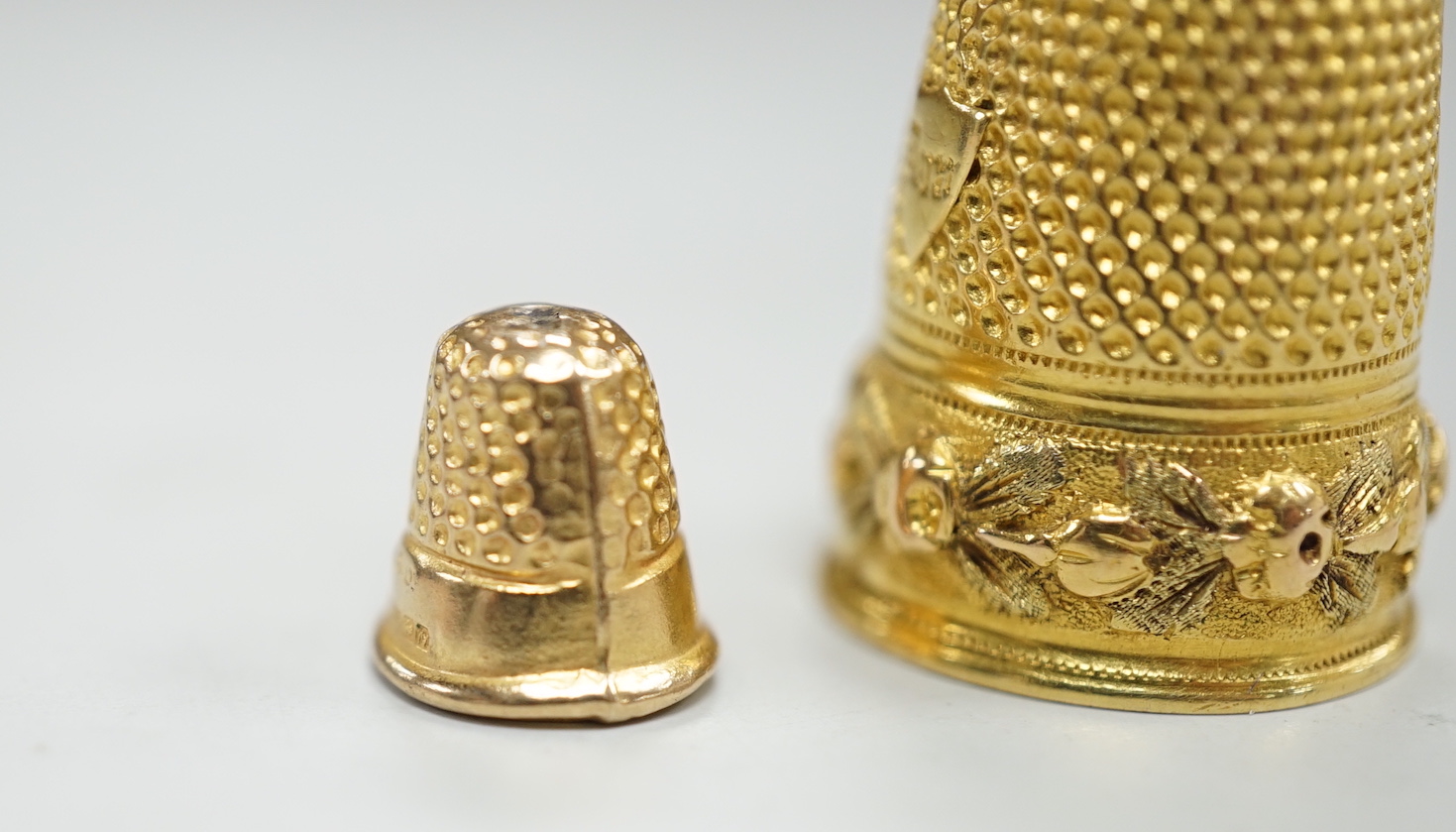 A French yellow metal (18ct poincon mark) thimble, 22mm, 5.4 grams and a tiny 1960's 9ct gold thimble, 9mm, 0.5 grams.
